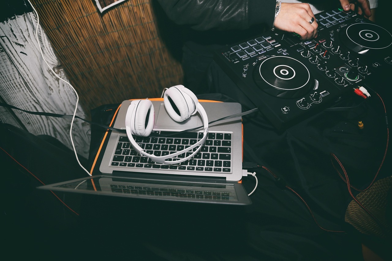 A flatlay of DJ equipment including headphones, laptop, and cables - the essentials for starting a mobile DJ business